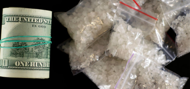 header roll of money and several baggies of crystal drugs