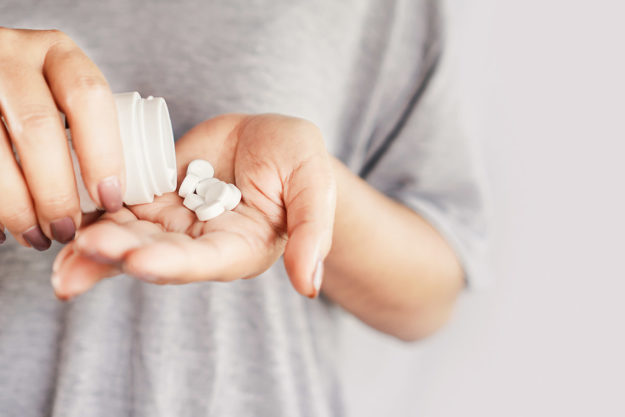 closeup woman hand holding medicine bottle taking overdose pills person showing the dangers of painkillers