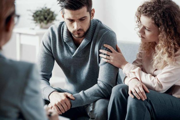 Supportive beautiful wife touching husband’s arm during psychoth loved one with an addiction in therapy