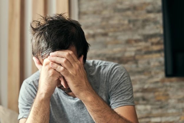 man sitting with his face in his hands thinking about heroin abuse